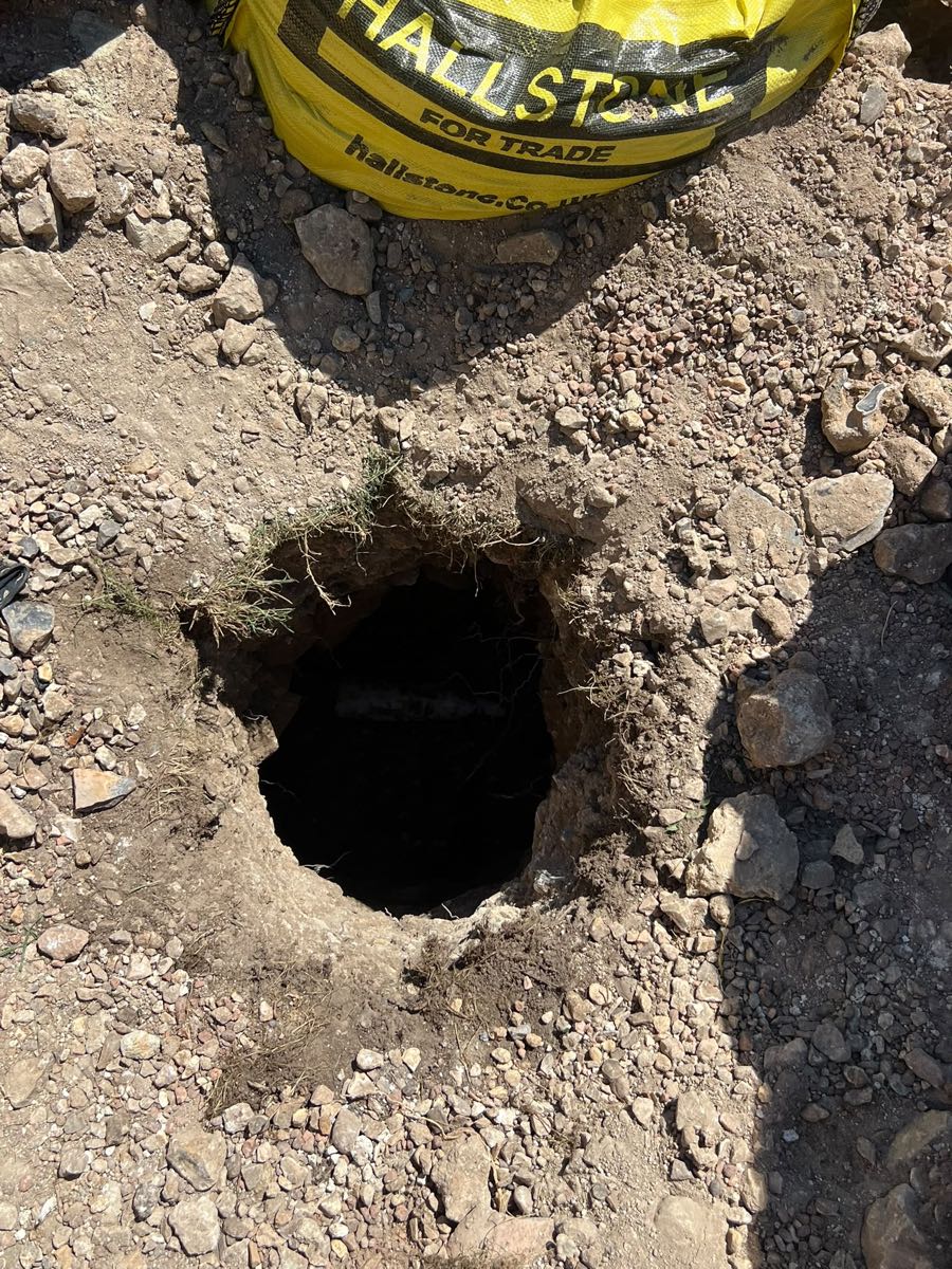 A dark void opened up in the ground beside a bag of aggregate