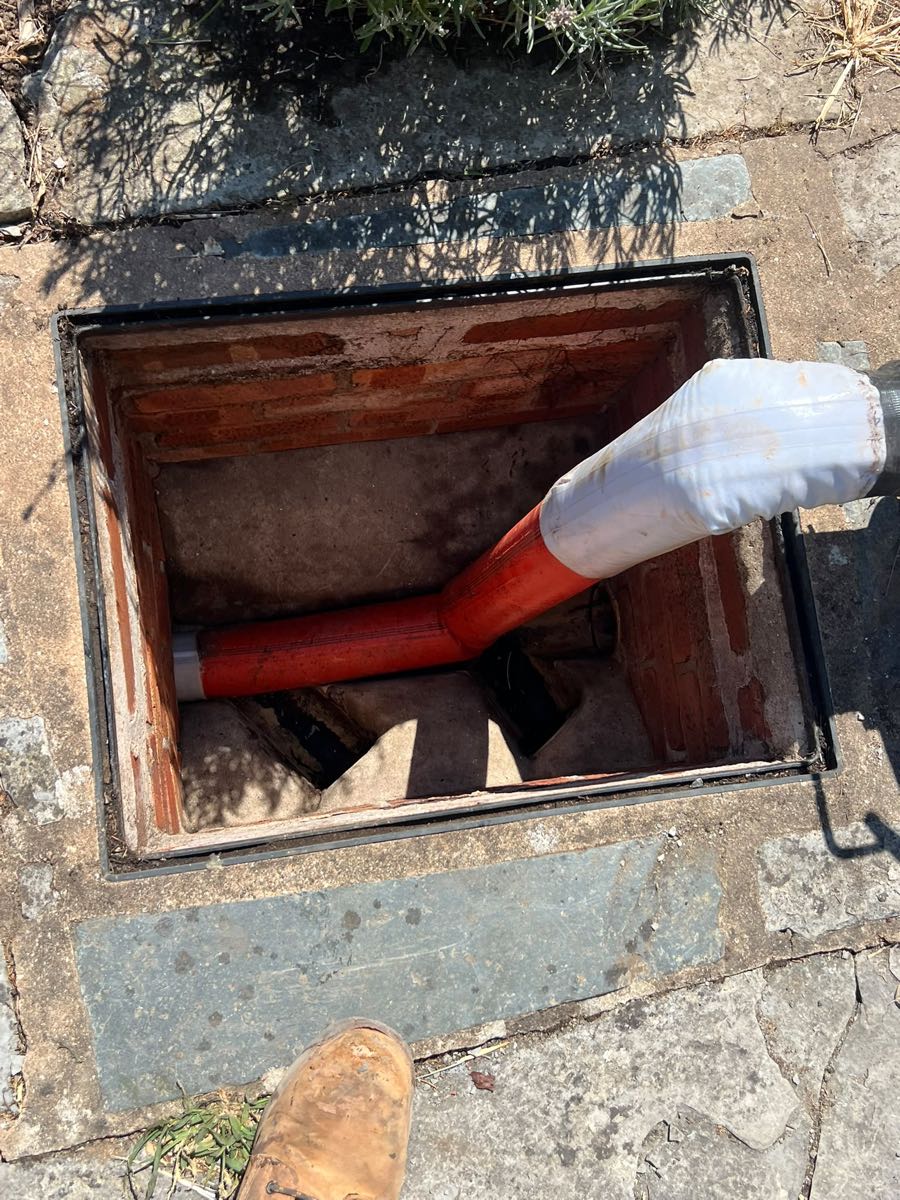 Jetting hose fed into an open brick inspection chamber in a patio