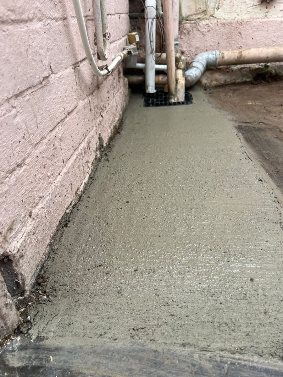 Close-up of a freshly concreted passage floor finished against the wall and gully