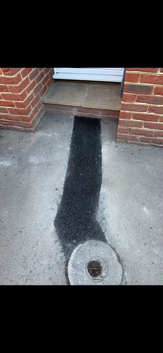 The same path with a fresh tarmac strip running from the doorstep to the round drain cover